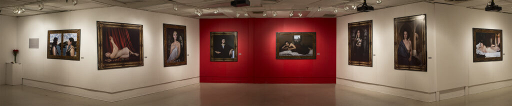 A panoramic view of the images installed in a gallery space. One wall of the gallery is red. 