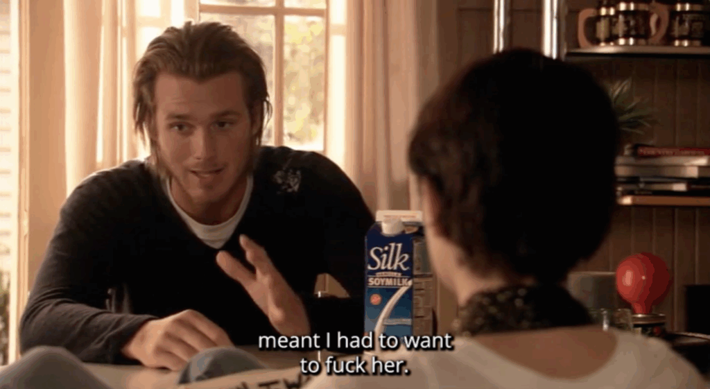 A white man sitting at a table. The subtitle text reads, "meant I had to want to fuck her"